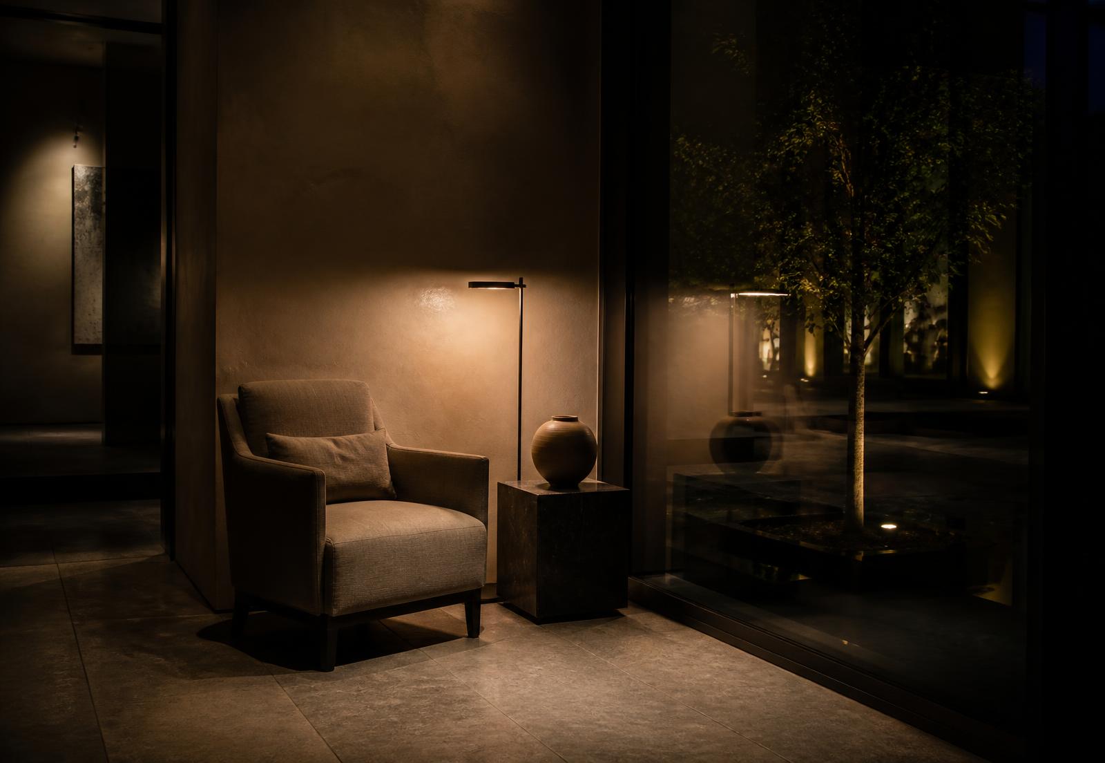 Quiet modern lounge corner lit by a single bronze lamp